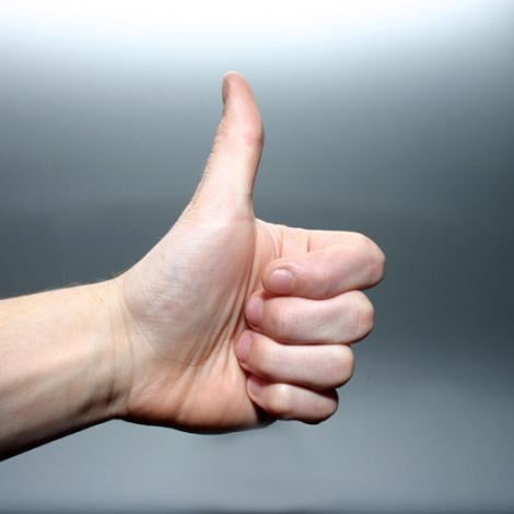 someone holding their left thumb in the thumbs up position